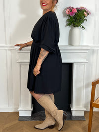 Cette robe courte noire grande taille, modèle Victoire, allie élégance et confort. Ses manches longues agrémentées de volants apportent une touche délicate et féminine, tandis que le col en V met subtilement en valeur le décolleté.