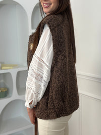 Adoptez l’élégance cosy avec cette veste sans manches marron effet moumoute. Confortable et tendance, elle se porte facilement sur vos tenues pour un look chic et décontracté. Son détail raffiné : une broche dorée amovible, qui apporte une touche lumineuse et personnalisable à votre style.