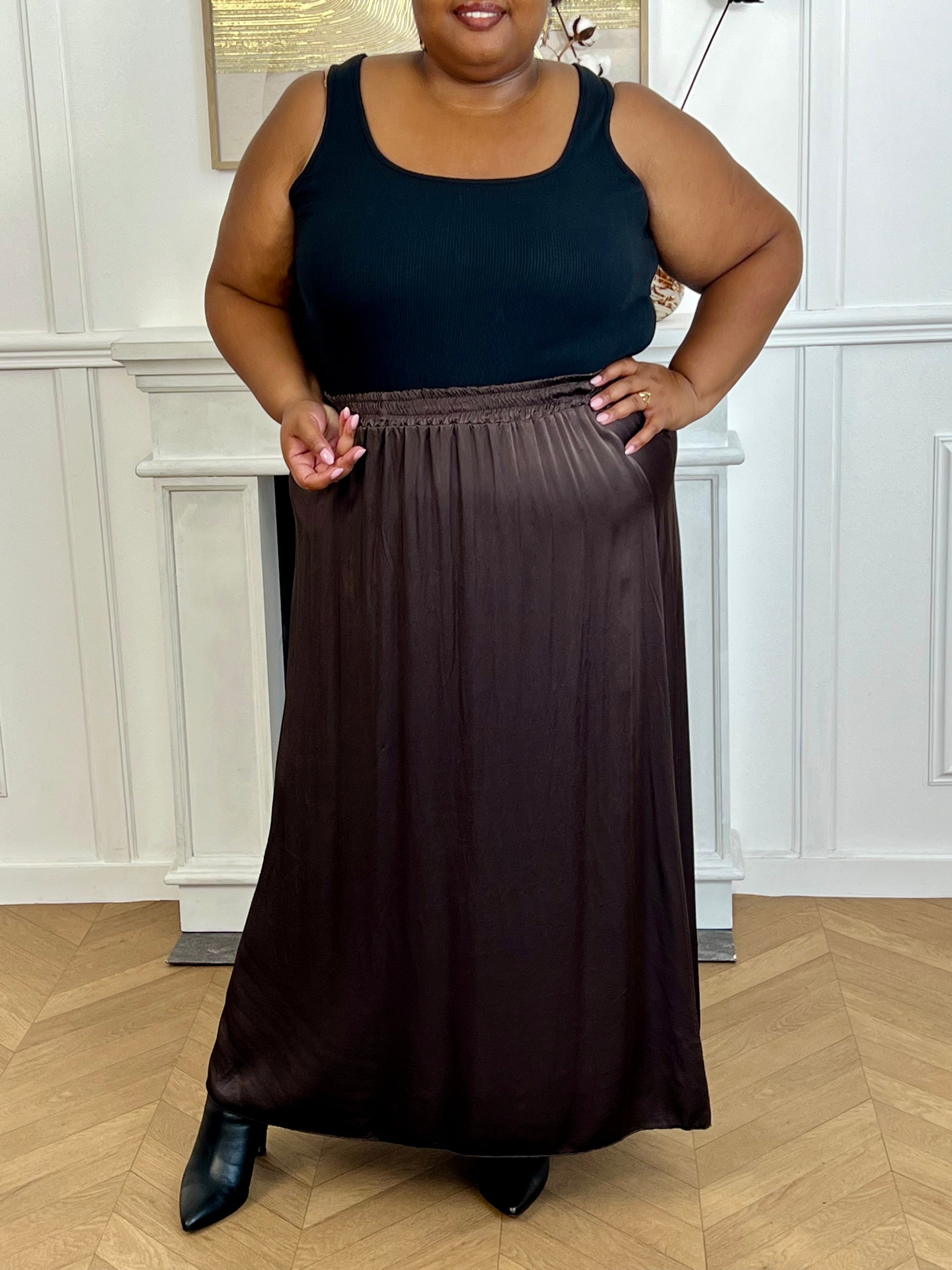 Cette jupe longue en satin marron, modèle Lola, allie élégance et confort grâce à sa taille élastique qui s'adapte parfaitement à toutes les morphologies.