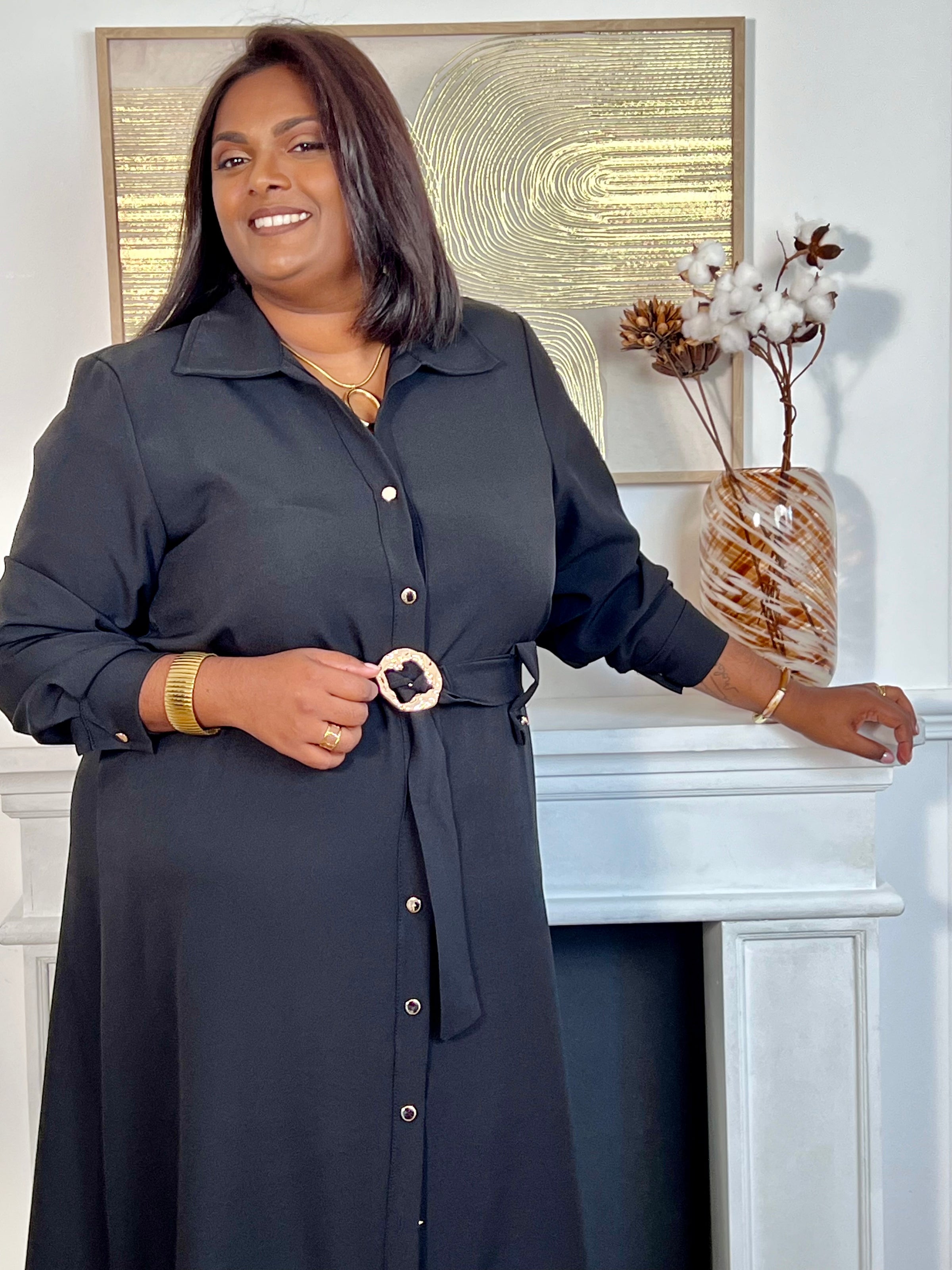 Cette robe longue noire grande taille, Agatha, allie élégance et confort. Dotée de manches longues et d’un col chemise, elle s’ouvre sur une série de boutons dorés tout au long du devant et aux manches, apportant une touche raffinée.