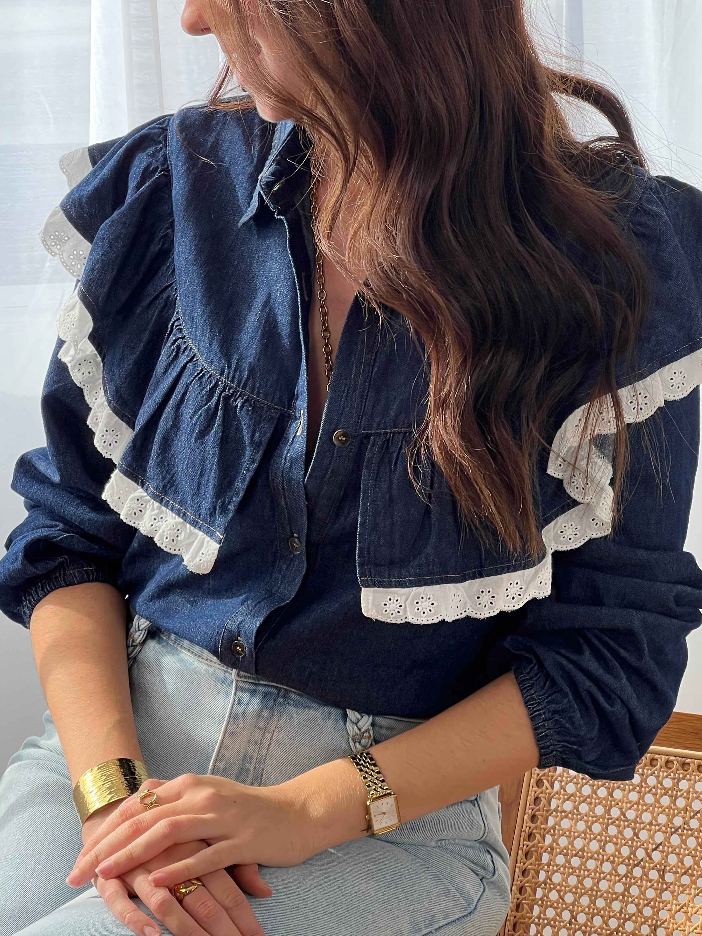 Cette chemise bleue Elyna allie élégance et confort avec son col classique et ses manches élastiques qui facilitent le mouvement. Les boutons sur toute la longueur permettent un enfilage pratique, tandis que le volant orné d'une broderie écrue apporte une touche délicate et raffinée.