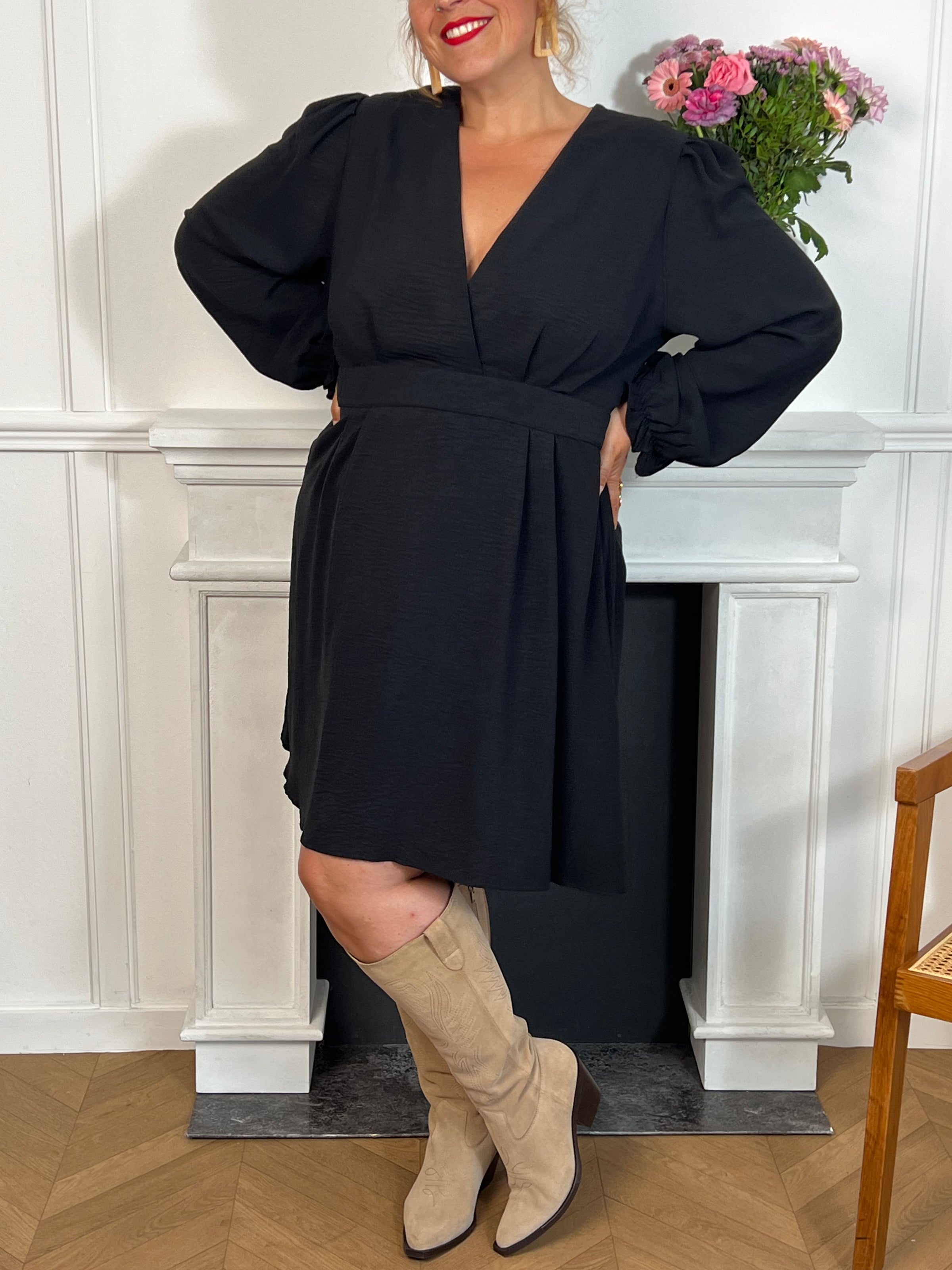 Cette robe courte noire grande taille, modèle Victoire, allie élégance et confort. Ses manches longues agrémentées de volants apportent une touche délicate et féminine, tandis que le col en V met subtilement en valeur le décolleté.