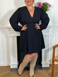 Cette robe courte noire grande taille, modèle Victoire, allie élégance et confort. Ses manches longues agrémentées de volants apportent une touche délicate et féminine, tandis que le col en V met subtilement en valeur le décolleté.