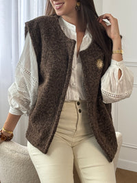 Adoptez l’élégance cosy avec cette veste sans manches marron effet moumoute. Confortable et tendance, elle se porte facilement sur vos tenues pour un look chic et décontracté. Son détail raffiné : une broche dorée amovible, qui apporte une touche lumineuse et personnalisable à votre style.