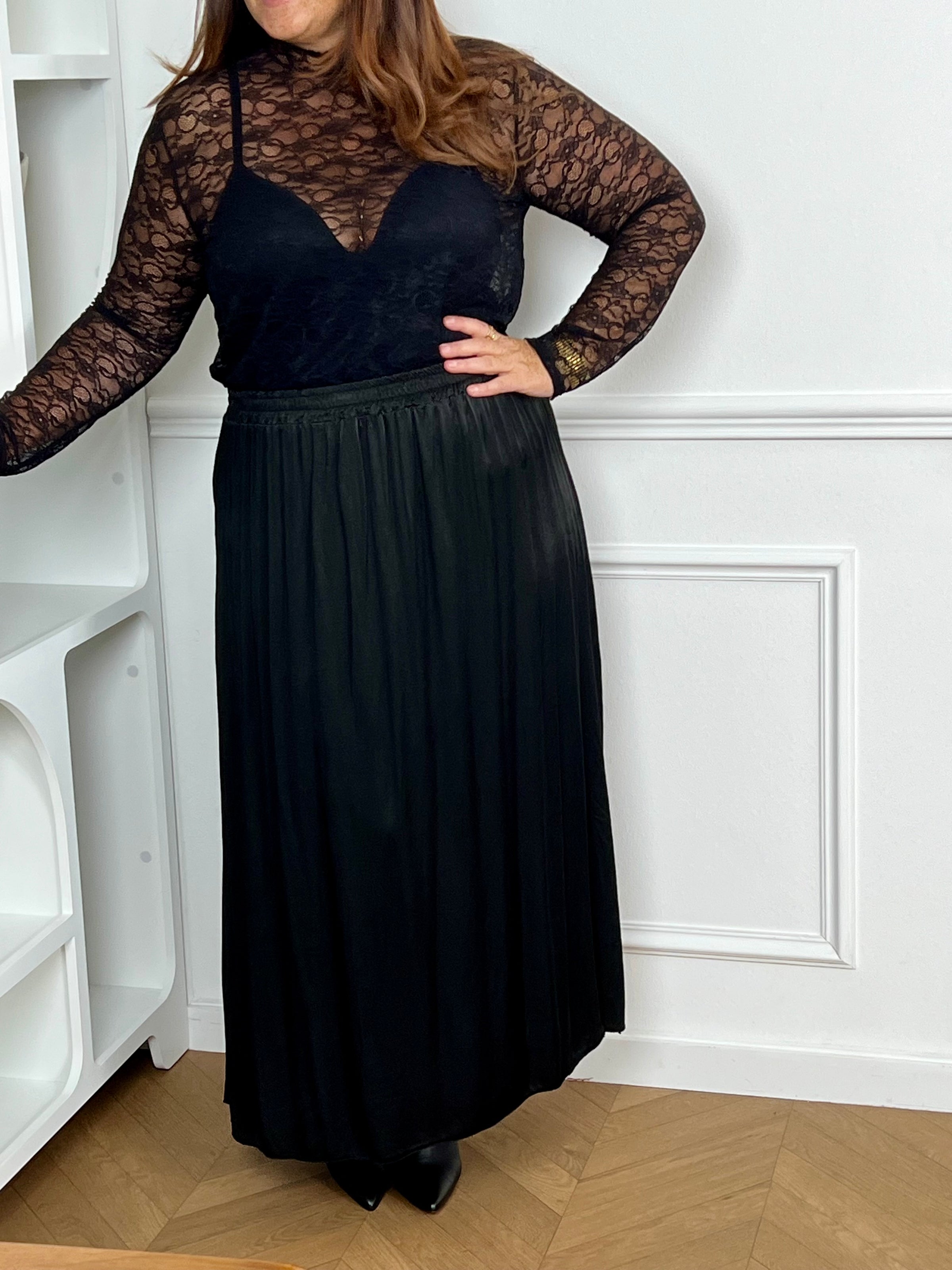 Cette jupe longue en satin noire, modèle Lola, allie élégance et confort grâce à sa taille élastique qui s'adapte parfaitement à toutes les morphologies.