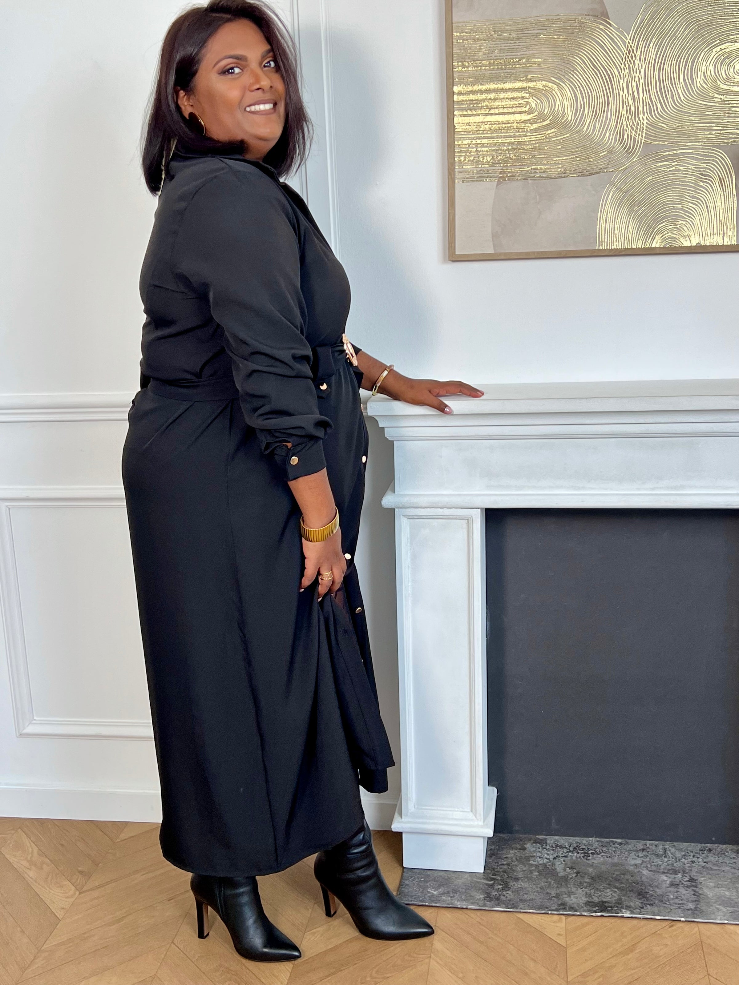 Cette robe longue noire grande taille, Agatha, allie élégance et confort. Dotée de manches longues et d’un col chemise, elle s’ouvre sur une série de boutons dorés tout au long du devant et aux manches, apportant une touche raffinée.