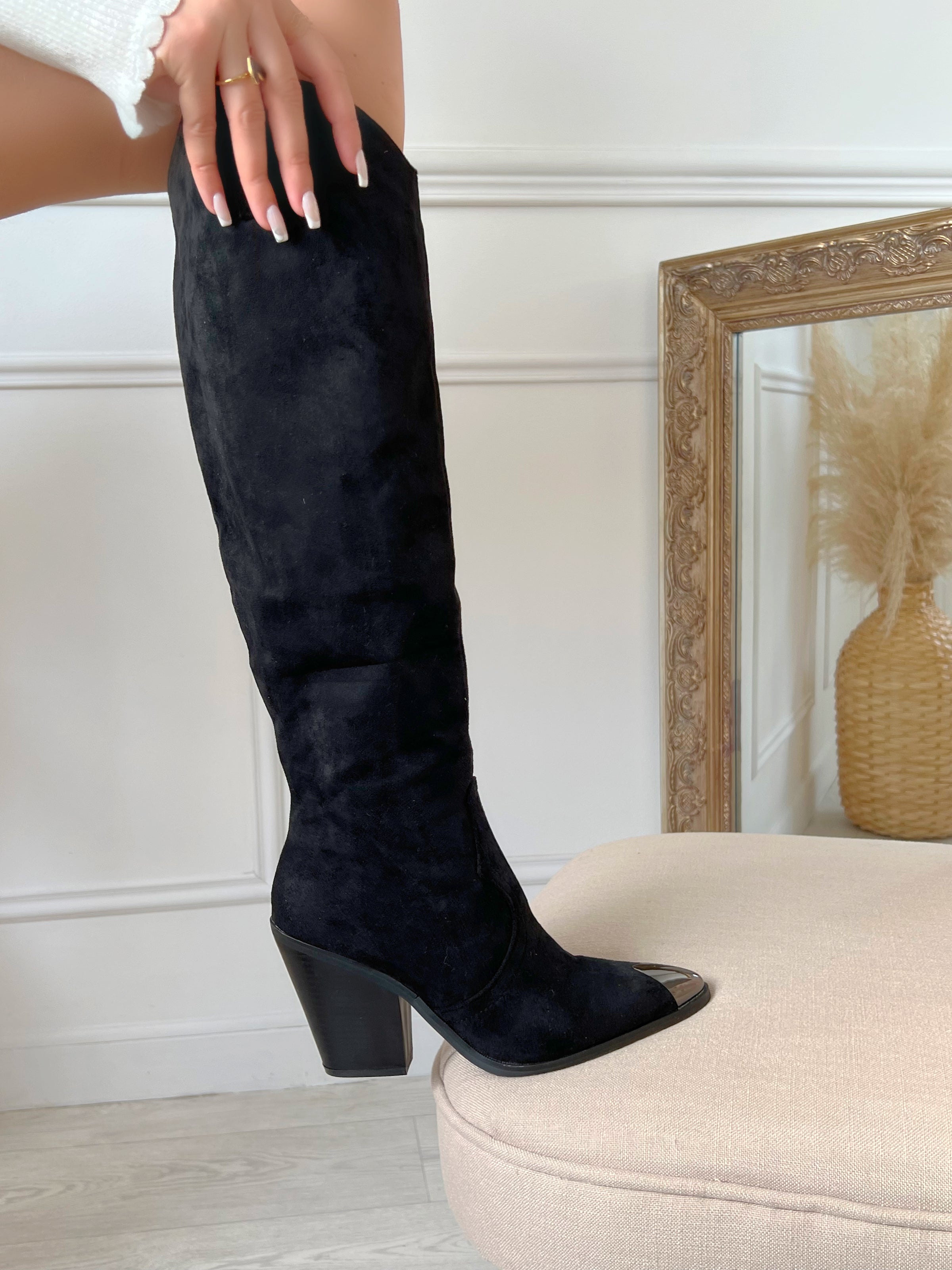 BOTTES SANTIAG NOIR DÉTAILS ARGENTÉ Bottes hautes type santiags Détail brillant sur le bout de la botte L’ouverture s’effectue sur le zip intérieur Taille normalement Couleur : noir Effet daim 100% Synthétique