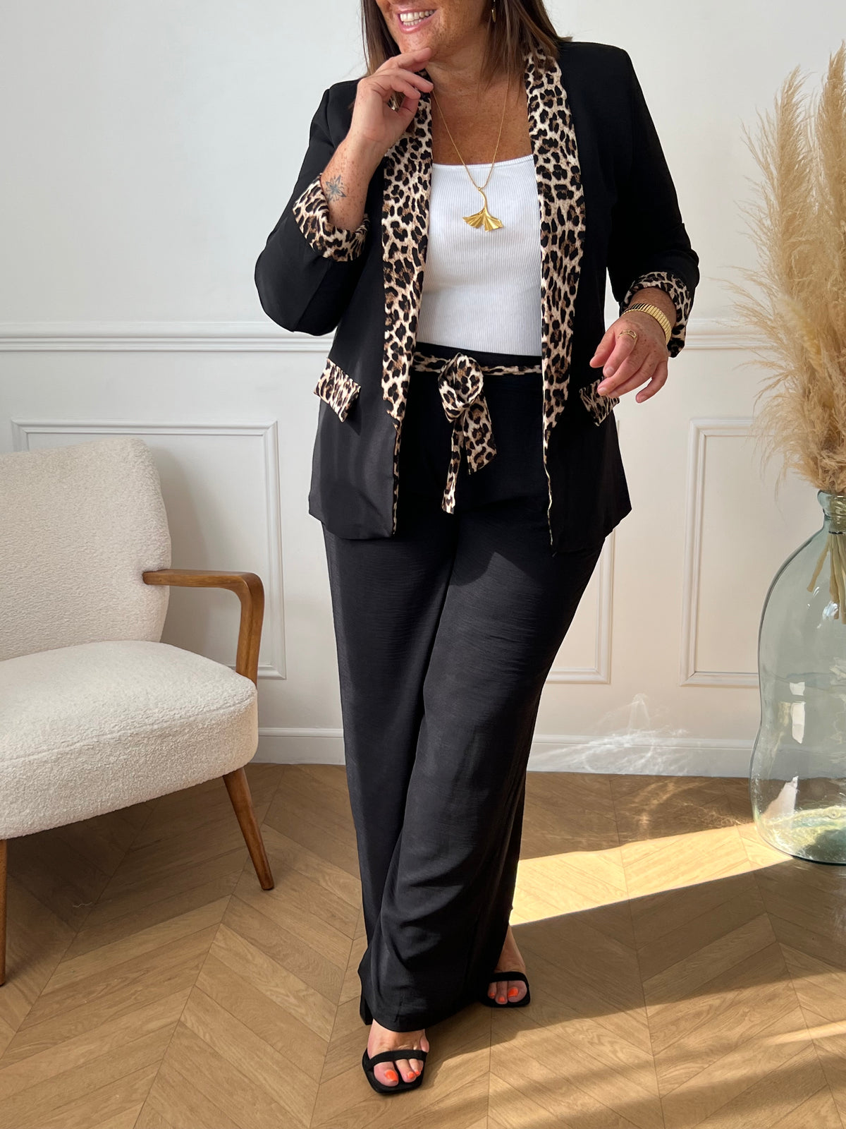 Ce blazer noir grande taille, nommé Axella, allie élégance et originalité. Ses manches longues et ses deux poches factices sur le devant offrent une silhouette structurée, tandis que le détail léopard qui court le long des poches et des revers de manches apporte une touche audacieuse et moderne.