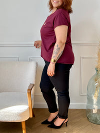 Tee-shirt bordeaux grande taille pour femme, manches courtes et col V élégant. Sa coupe moderne plus longue à l’arrière offre confort et style. Détail chic : inscription dorée "Love". Couleurs tendance bordeaux et doré, idéal pour un look casual et féminin