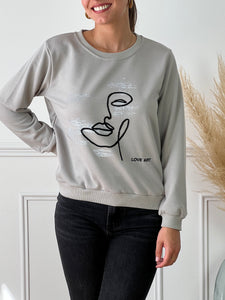 Pull gris avec motif noir et argent femme Pull manches longues Col rond Resserré aux niveau des poignets Détails argenté et broderie noir visage et "Love art' Couleur : gris, argent et noir Composition : 65% Coton, 35% Polyester Made in P.C.R