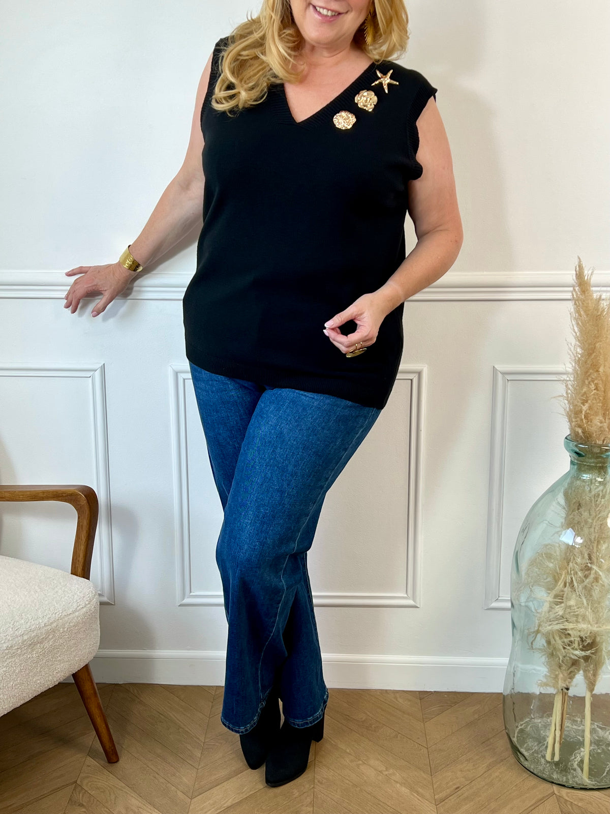 Ce pull sans manches grande taille Shanney allie élégance et confort avec son col en V et ses broches dorées modulables. Disponible en noir avec des détails dorés, il apporte une touche raffinée à votre tenue en toute simplicité.