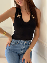 Élégant et plein de caractère, ce top noir se distingue par ses bretelles fendues ornées de délicates étoiles dorées. Une pièce raffinée et originale, parfaite pour illuminer une tenue du soir ou apporter une touche de glamour à un look quotidien.