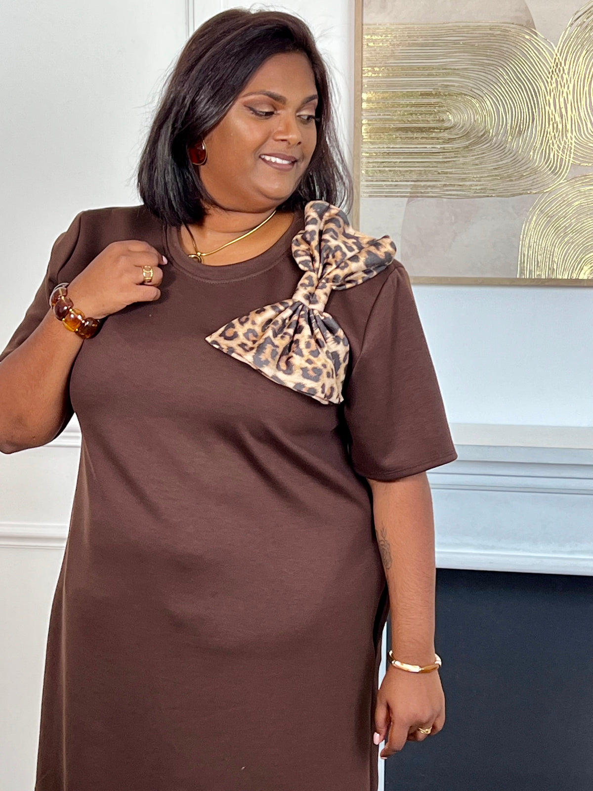 Adoptez un style chic avec cette robe courte marron grande taille à manches courtes et col rond. Son nœud motif léopard sur le devant apporte une touche élégante et tendance. Confectionnée dans une matière épaisse et confortable, elle est disponible en noir, marron et beige.