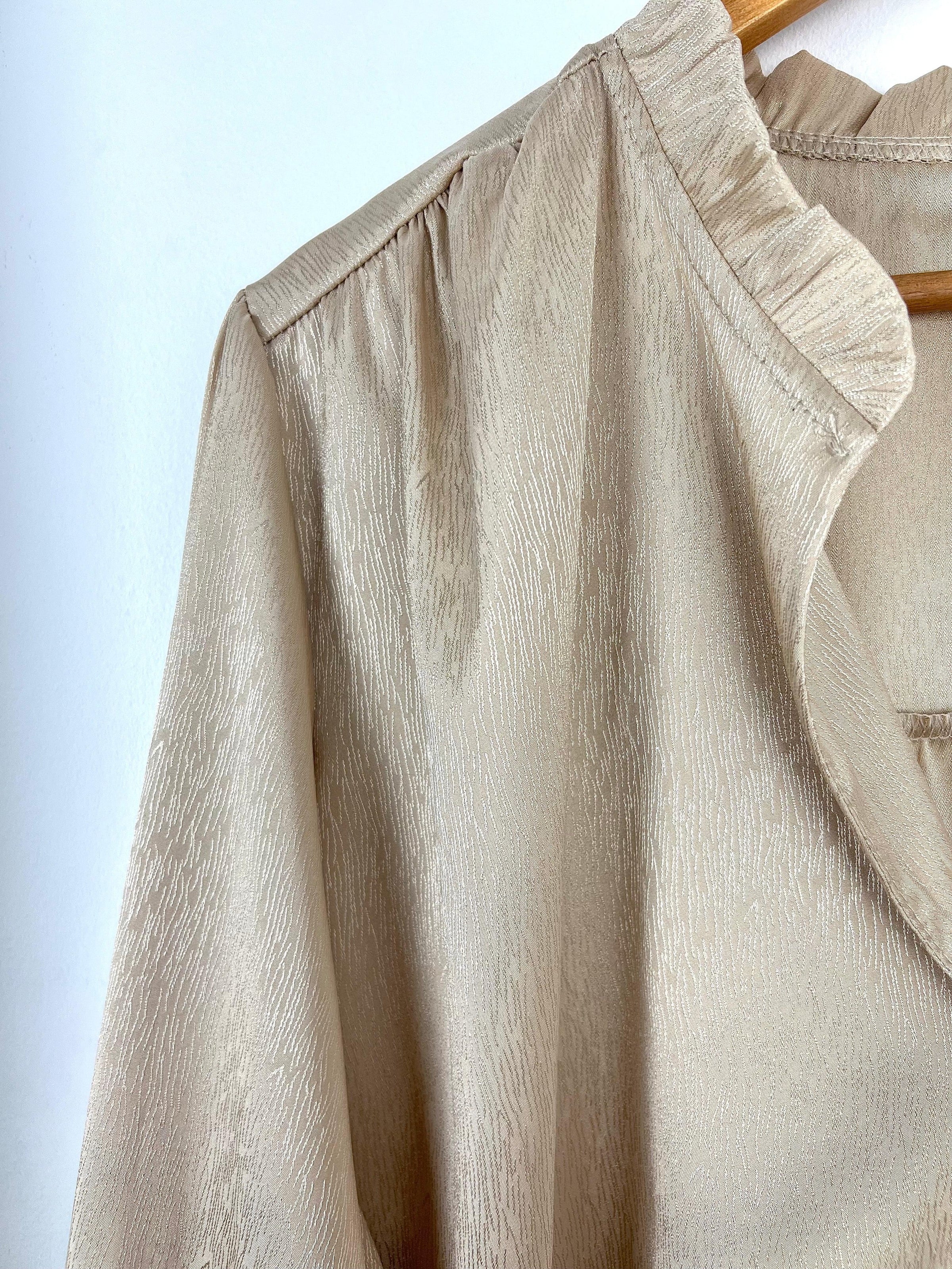 La chemise beige avec volants est un classique de la garde-robe féminine. Elle est à la fois élégante, féminine et versatile. Elle peut être portée pour toutes les occasions, du quotidien au travail en passant par les occasions spéciales.