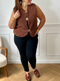 La veste moumoute sans manches Eda allie douceur et style. Conçue pour offrir un confort optimal, elle présente un col en V élégant et des broches dorées délicates sur le devant, qui ajoutent une touche sophistiquée.