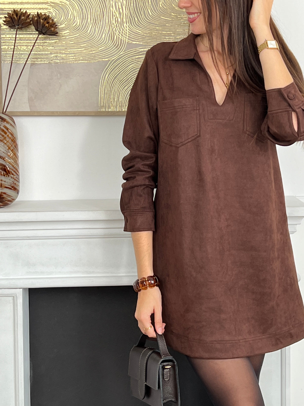 Adoptez un style élégant et confortable avec cette robe marron effet daim. Sa coupe ample offre une liberté de mouvement idéale, tandis que le col chemise en V et les boutons aux poignets ajoutent une touche raffinée.