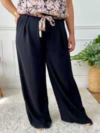 Ce pantalon noir grande taille Karoline est un essentiel pour toutes les femmes. Très confortable avec son élastique au dos et ses poches latérales à l'avant, il ajoute une touche de style avec sa ceinture amovible à motifs assortie avec le top Alena.