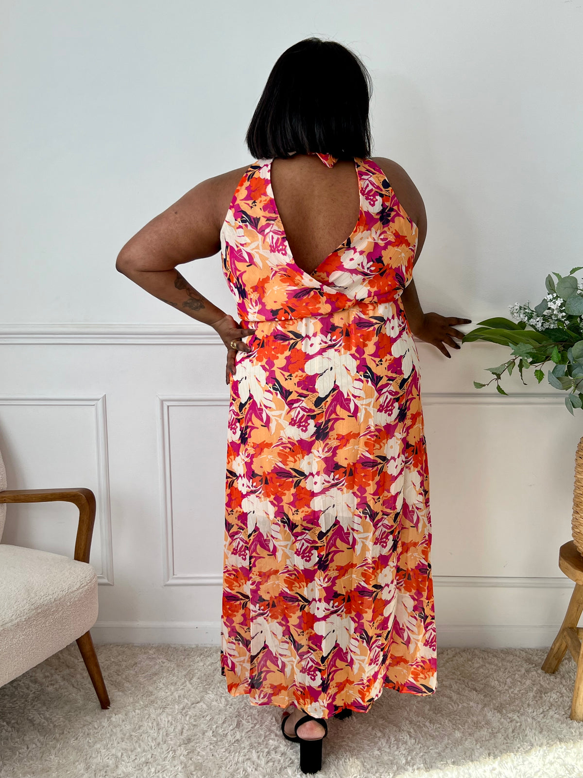 Découvrez notre robe longue Manuela en orange, avec un délicat motif floral et des détails dorés pour un look lumineux. Avec son col cache cœur à l'avant et à l'arrière, elle est à la fois élégante et confortable grâce à son élastique à la taille et son lien à nouer à la nuque. Parfaite pour une soirée d'été !