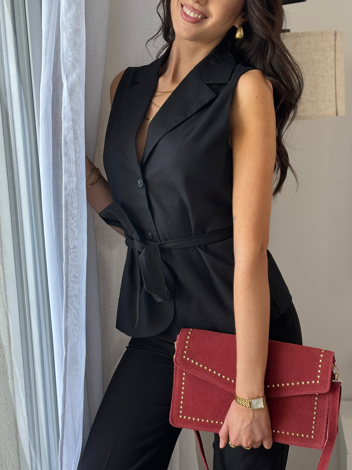 La veste sans manches Luciana est le choix parfait pour une tenue sophistiquée. Avec son effet blazer, cette veste noire sans manches apporte une touche élégante à n'importe quelle tenue. Les boutons sur le devant et la ceinture amovible offrent une coupe cintrée flatteuse pour mettre en valeur votre silhouette. Un must-have pour votre garde-robe.