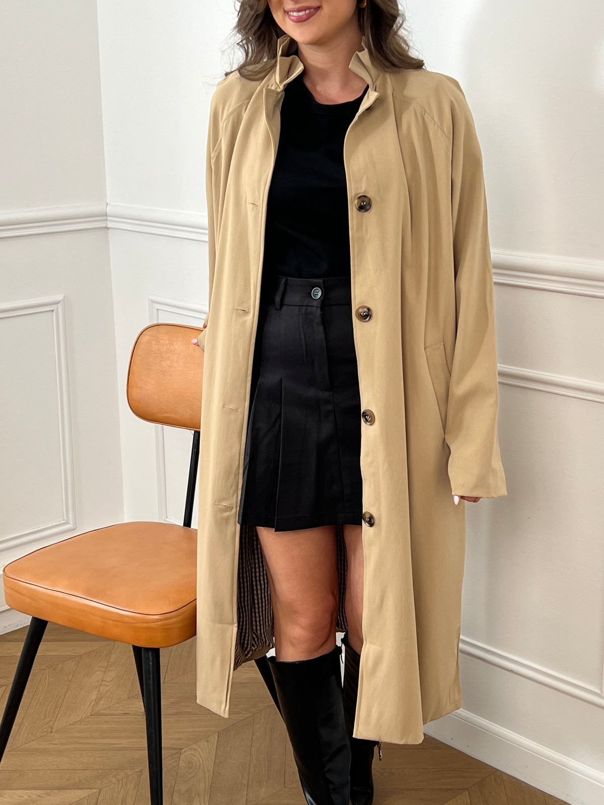Trench beige femme avec ceinture, manches longues et col volanté pour une touche féminine. Boutons tout le long, doublure intérieure en carreaux vichy marron et écru, offrant élégance et confort. Coupe ample et deux poches latérales pratiques.