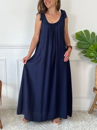 Sa coupe ample assure un confort optimal tout au long de la journée. Sans manches, elle présente des liens à nouer aux épaules pour une touche élégante et ajustable. Son col rond, à l’avant comme à l’arrière, est agrémenté d’un élastique qui garantit un maintien parfait sans contrainte.