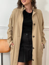 Trench beige femme avec ceinture, manches longues et col volanté pour une touche féminine. Boutons tout le long, doublure intérieure en carreaux vichy marron et écru, offrant élégance et confort. Coupe ample et deux poches latérales pratiques.