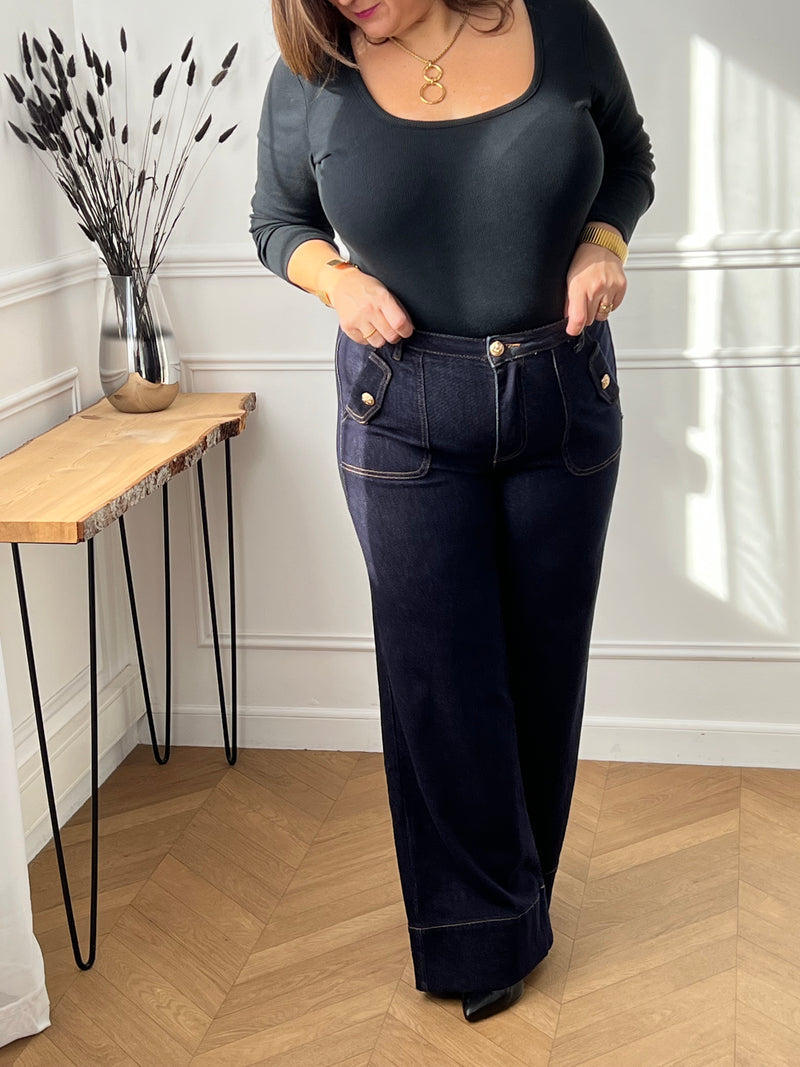 Jean bleu foncé intemporel au style affirmé. Coupe large et confortable avec jambes évasées pour une silhouette moderne. Doté de 4 poches pratiques et de détails dorés aux poches qui ajoutent une touche d'élégance.