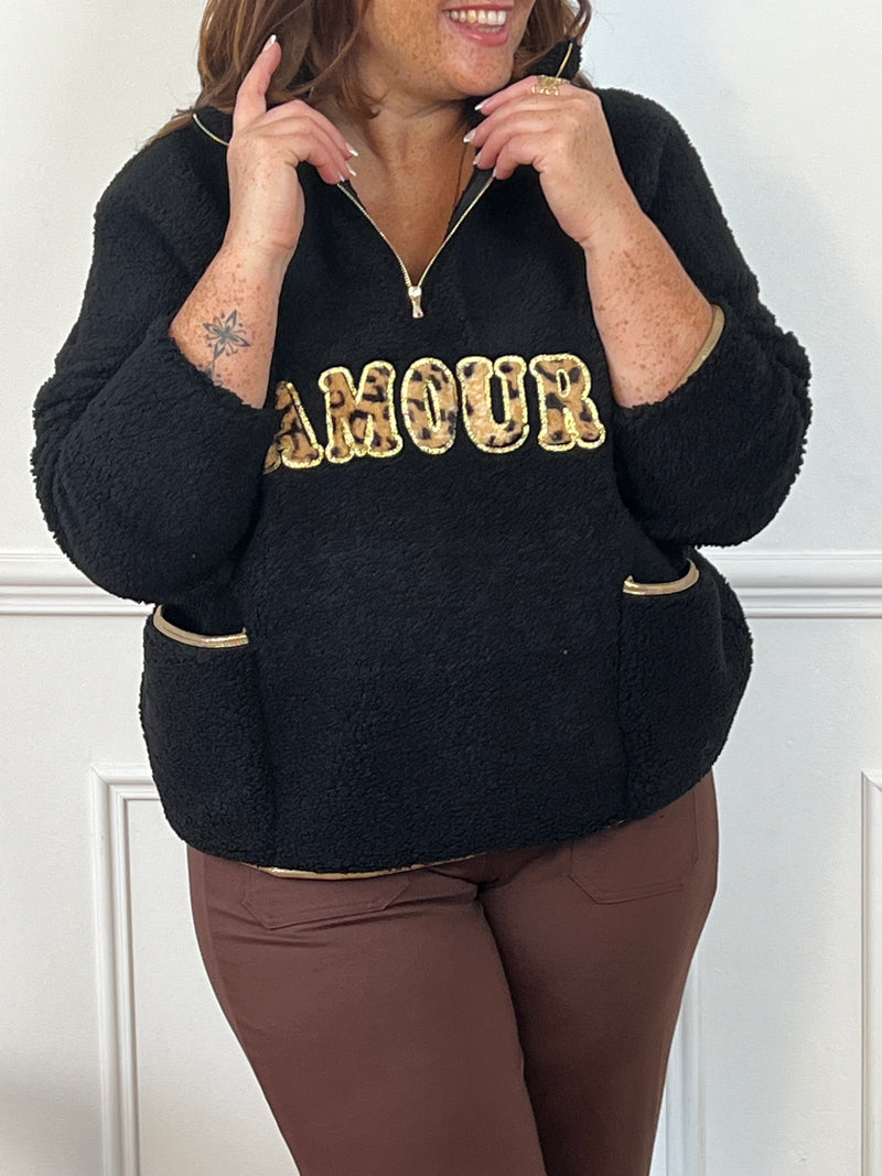 Craquez pour ce pull ultra-doux "Amour" ! Avec son col montant zippé et son détail doré, il allie confort et style. L'effet moumoute et les deux poches avant ajoutent une touche cosy et tendance.