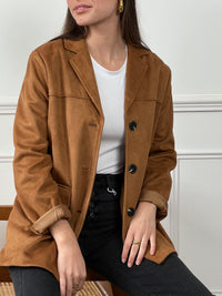 Adoptez une allure élégante et cosy avec cette veste douce en coloris camel. Confectionnée dans une matière effet daim, elle allie style et confort pour vous accompagner en toute occasion. Ses manches longues et ses boutons sur la longueur apportent une touche classique, tandis que ses deux poches factices à l’avant ajoutent une note chic et minimaliste.