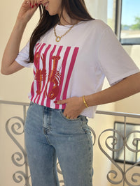 Le tee-shirt écru Adelina offre un col V et manches courtes, avec des motifs homards et traits fuchsia pour une touche colorée et originale.
