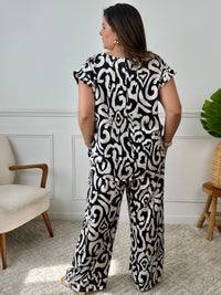 Léger et éclatant, ce top fluide noir et écru sans manches séduit par ses jolis volants aux épaules. Une pièce pleine de fraîcheur et de féminité, parfaite pour égayer vos looks avec une touche raffinée.