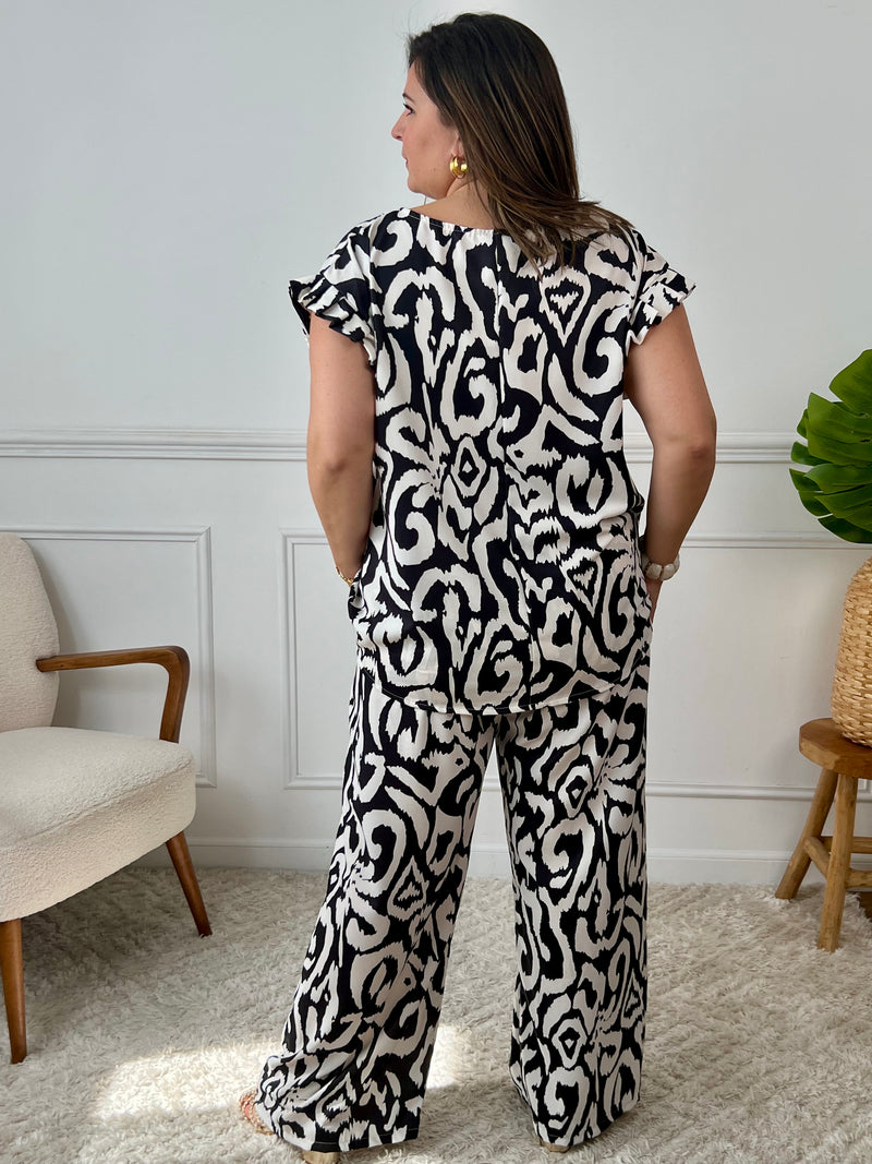 Léger et éclatant, ce top fluide noir et écru sans manches séduit par ses jolis volants aux épaules. Une pièce pleine de fraîcheur et de féminité, parfaite pour égayer vos looks avec une touche raffinée.