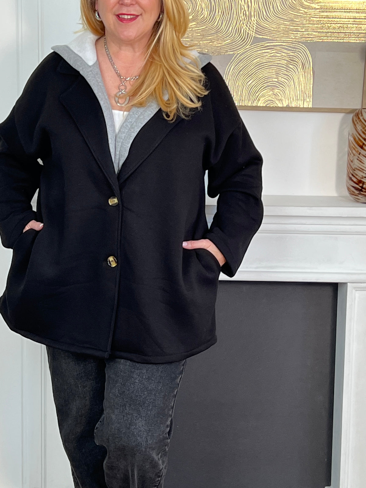 Chic et pratique, ce manteau noir à manches longues séduit par sa capuche amovible effet sweat gris. Une pièce moderne et polyvalente qui offre à la fois chaleur, confort et élégance au quotidien.