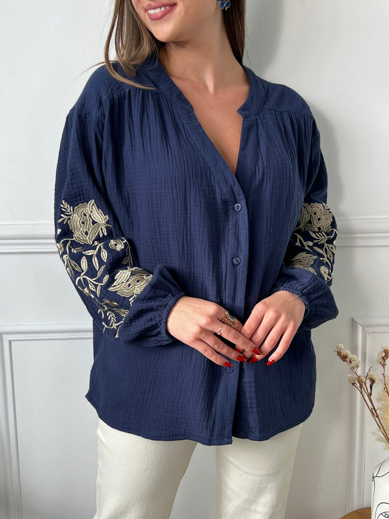 Cette chemise bleue pour femme allie élégance et raffinement grâce à ses détails dorés uniques. Conçue avec des manches longues et un col en V flatteur, elle se distingue par de sublimes broderies florales dorées sur les manches, ajoutant une touche de sophistication et de charme. Boutonnée sur toute la longueur, cette chemise est facile à porter pour un look chic et stylé en toutes occasions. 