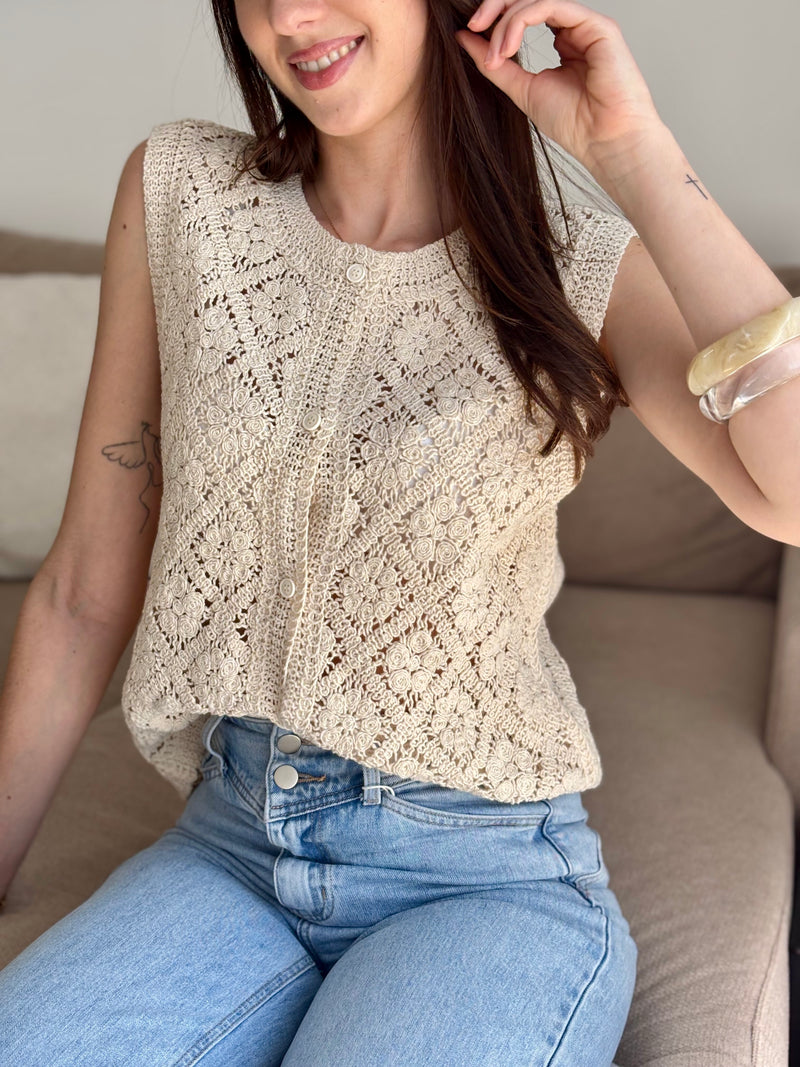Rejoignez la tendance du crochet avec le top sans manches Liyah ! Avec son col rond et ses boutons sur la longueur, ce top apporte une touche vintage et bohème à votre garde-robe.