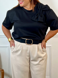 Tee-shirt noir grande taille pour femme, ce tee-shirt à manches courtes est doté d’un col rond et d’un nœud sur le devant pour une touche féminine. Confectionné dans une matière épaisse pour un tombé structuré. Couleur noir, idéale pour la mi-saison.