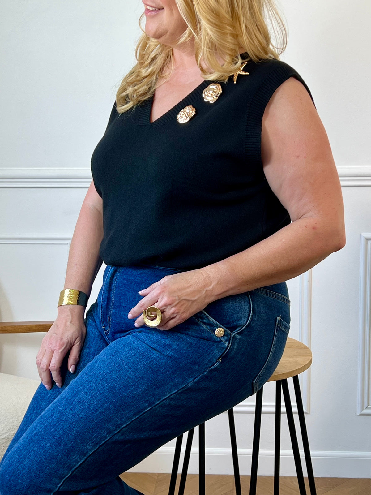 Ce pull sans manches grande taille Shanney allie élégance et confort avec son col en V et ses broches dorées modulables. Disponible en noir avec des détails dorés, il apporte une touche raffinée à votre tenue en toute simplicité.