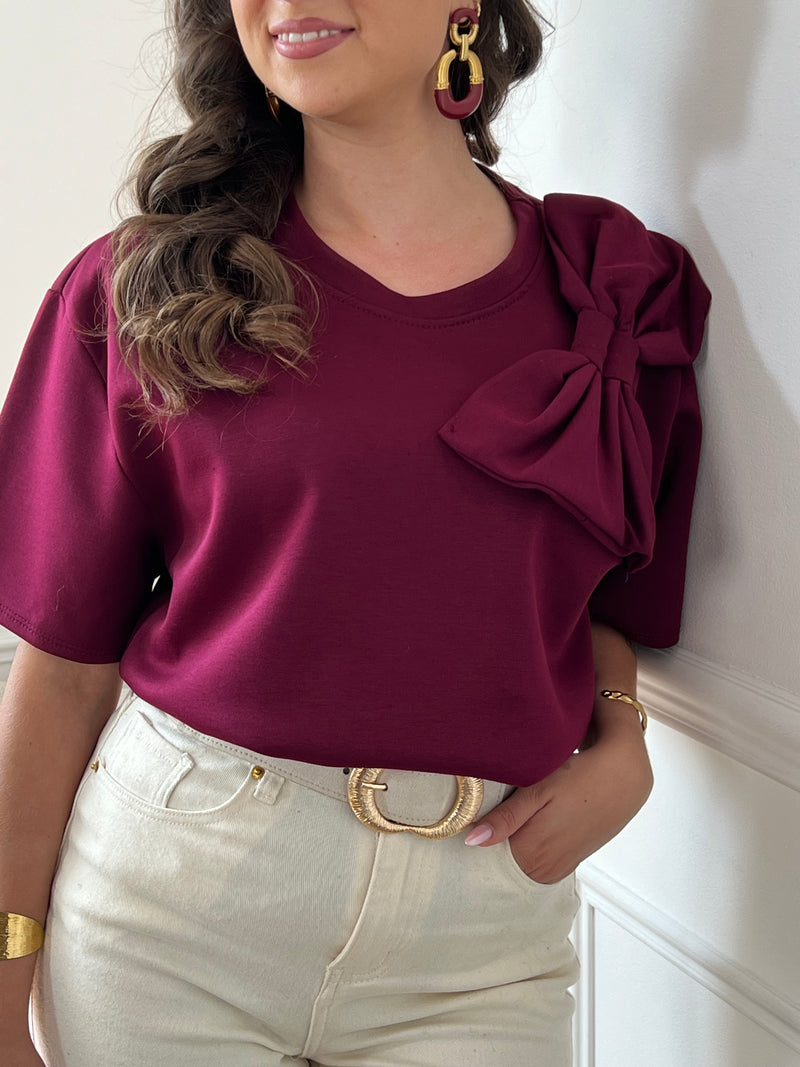 Tee-shirt bordeaux pour femme – Ce tee-shirt à manches courtes est doté d’un col rond et d’un nœud sur le devant pour une touche féminine. Confectionné dans une matière épaisse pour un tombé structuré. Couleur bordeaux, idéale pour la mi-saison.