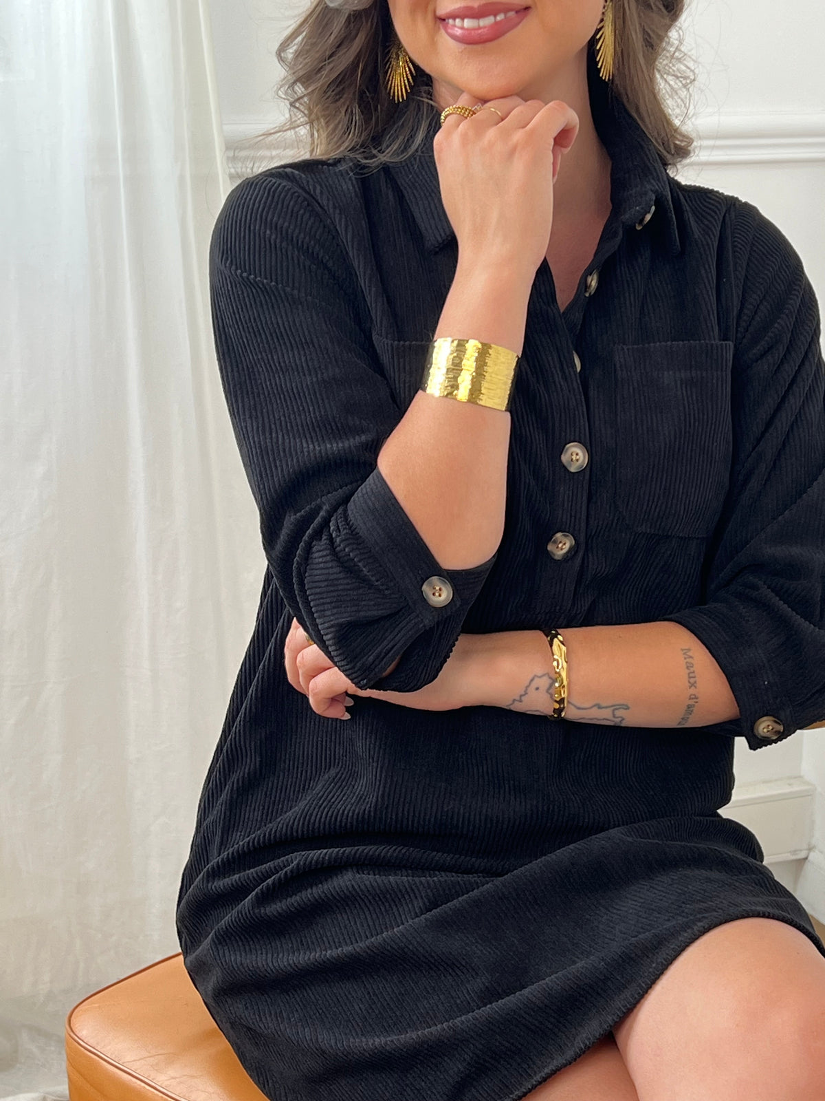 Cette robe courte noire, modèle Cora, allie élégance et confort. Ses manches longues et son col chemise apportent une touche sophistiquée, tandis que les boutons au col et aux manches accentuent son style raffiné.