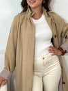 Trench beige femme avec ceinture, manches longues et col volanté pour une touche féminine. Boutons tout le long, doublure intérieure en carreaux vichy marron et écru, offrant élégance et confort. Coupe ample et deux poches latérales pratiques.