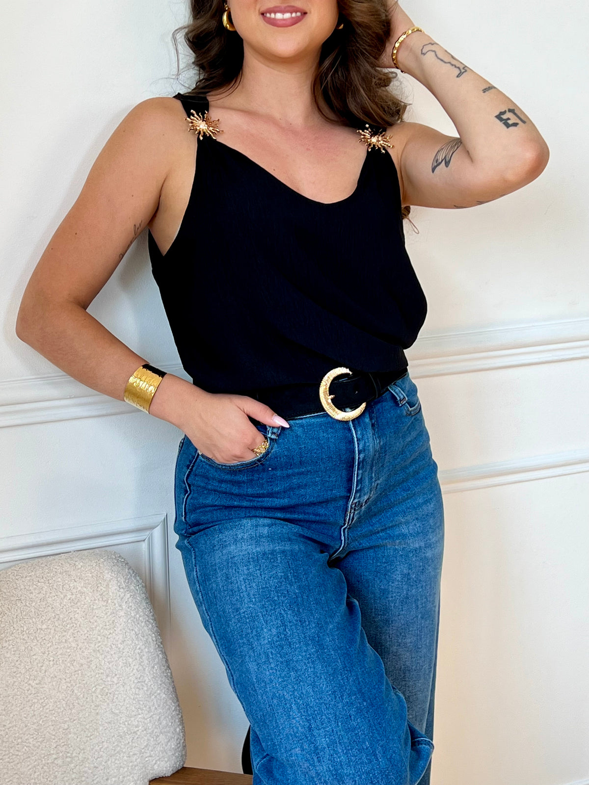 Ce top noir au design épuré séduit par ses bretelles ornées de délicats détails dorés. À la fois sobre et raffiné, il apporte une touche d’élégance à vos looks, de jour comme de nuit.