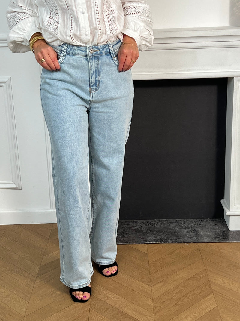 Jean bleu clair pour femme au style moderne et confortable, idéal pour un look tendance au quotidien. Ce modèle est doté de deux poches à l’avant et à l’arrière, de passants pour ceinture, ainsi que d’une fermeture éclair et d’un bouton pratique. Les détails tressés sur le devant apportent une touche originale et élégante à ce jean bleu incontournable.