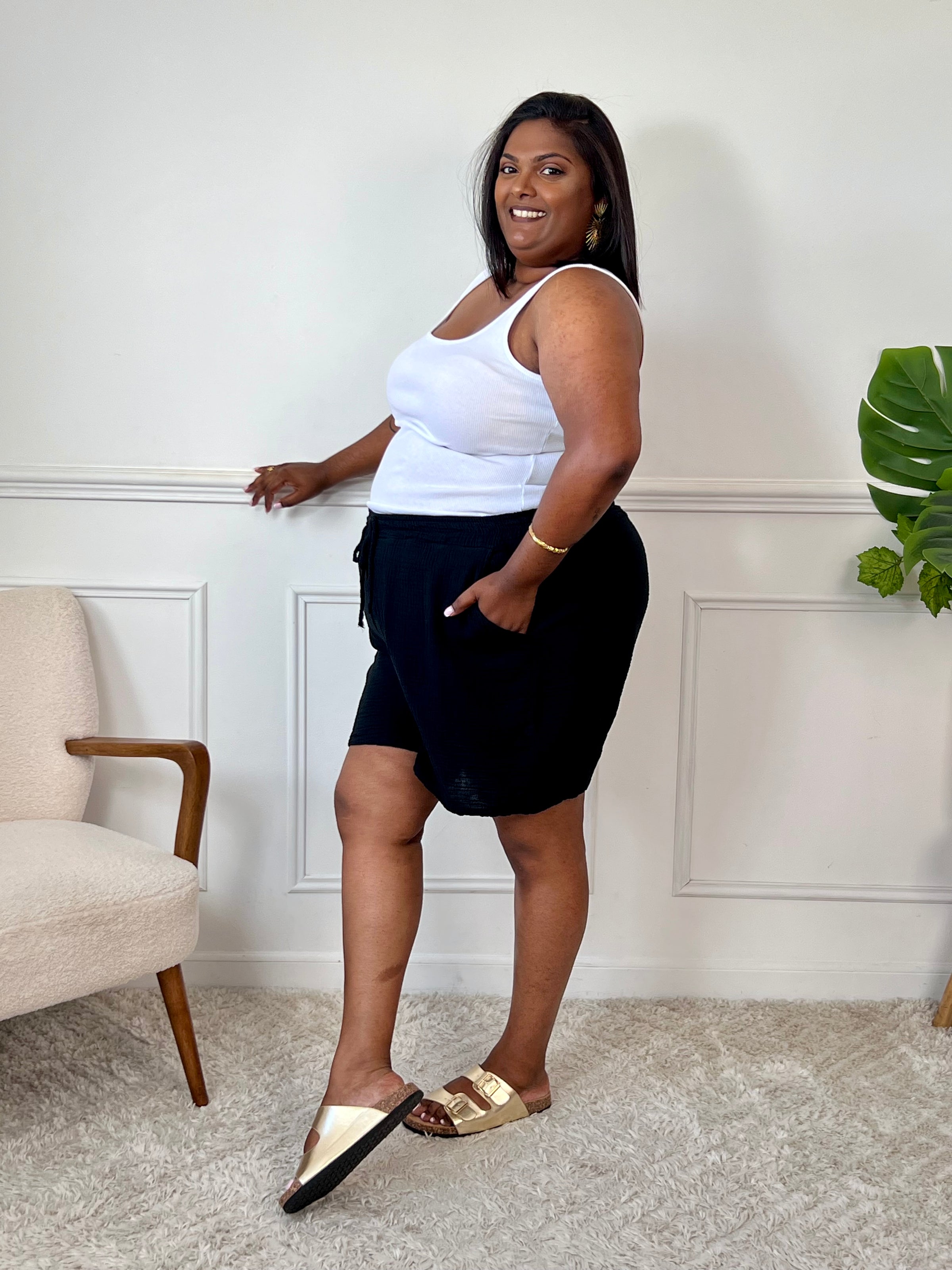 Ce short noir en gaze de coton allie confort et praticité grâce à sa taille élastique ajustable par un lien de serrage. Ses deux poches latérales offrent un espace pratique pour vos essentiels, tandis que sa matière légère assure une agréable sensation de douceur sur la peau.