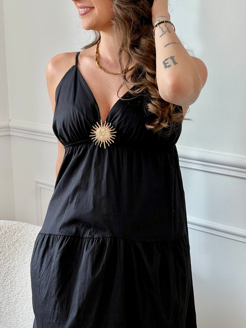 Cette robe longue noire, Elenora, allie élégance et confort grâce à ses bretelles réglables et sa taille élastique qui s’adaptent parfaitement à votre silhouette. Son col en V met en valeur le décolleté, tandis que le détail doré en forme de soleil apporte une touche lumineuse et raffinée sur la poitrine.