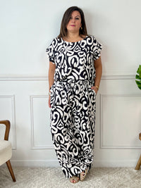 Léger et éclatant, ce top fluide noir et écru sans manches séduit par ses jolis volants aux épaules. Une pièce pleine de fraîcheur et de féminité, parfaite pour égayer vos looks avec une touche raffinée.
