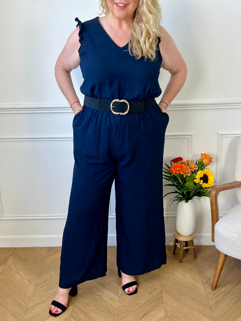 Cette combinaison longue bleue Curve : Liona, une pièce incontournable pour les femmes de grande taille. Avec son col V flatteur, sa taille élastique et son dos nu élégant, elle est à la fois pratique et chic. Ses poches latérales et volants aux épaules ajoutent une touche de style. Disponible en bleu marine et noire