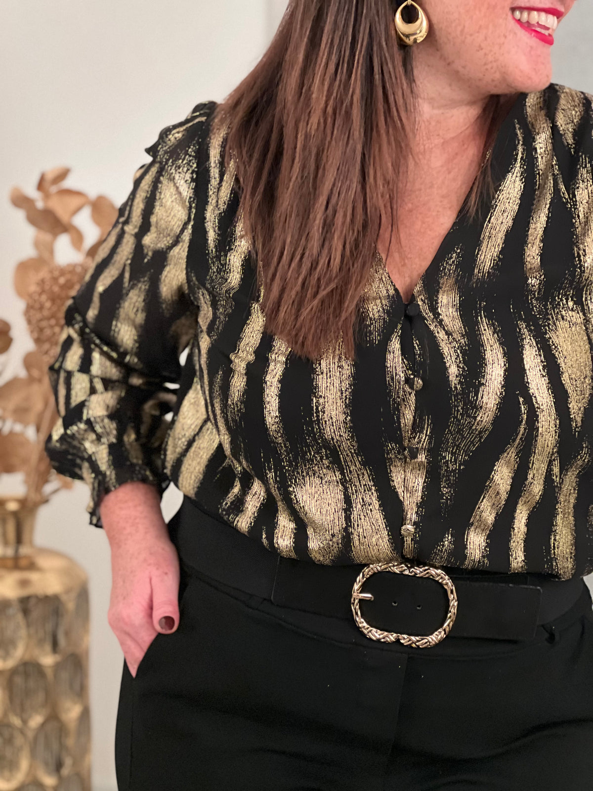 Découvrez la chemise Laina, une pièce festive qui allie élégance et confort. Avec son col V plongeant et ses manches longues ornées de volants délicats, elle crée une silhouette flatteuse et sophistiquée.