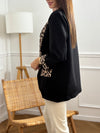 Ce blazer noir, nommé Axella, allie élégance et originalité. Ses manches longues et ses deux poches factices sur le devant offrent une silhouette structurée, tandis que le détail léopard qui court le long des poches et des revers de manches apporte une touche audacieuse et moderne.