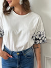 Découvrez notre magnifique Tee-shirt Adalia, avec son col rond et ses manches courtes confortables. Les motifs floraux sur les manches ajoutent une touche de féminité, tandis que le motif brodé ajouré apporte une élégance subtile. Fabriqué en coton, ce tee-shirt est à la fois doux et confortable. Profitez d'un style unique avec Adalia !