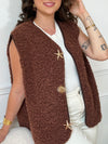 La veste moumoute sans manches Eda allie douceur et style. Conçue pour offrir un confort optimal, elle présente un col en V élégant et des broches dorées délicates sur le devant, qui ajoutent une touche sophistiquée.